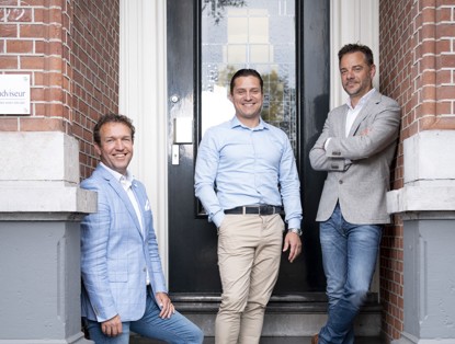 Drie mannen in zakelijke kleding staan en zitten voor een deur, waarbij de nadruk ligt op hun houdingen en de omgeving.