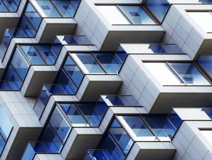 Close-up van een modern appartementencomplex met een golvende gevel en talrijke glazen balkons.