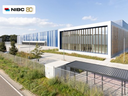 Moderne kantoorgebouwen met grote ramen en blauwe panelen, gelegen langs een straat en omringd door groen.