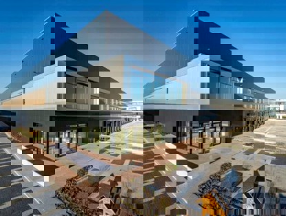 Moderne distributiecentrum met grote ramen en een strakke, zwarte gevel, omgeven door een parkeerplaats.