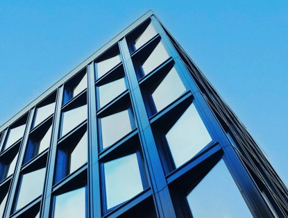 Modern kantoorgebouw met een blauwe glazen gevel en een opvallende architectuur.